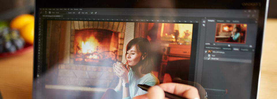 Photographer using a stylus pen to edit a low-light portrait in Adobe Lightroom on a laptop