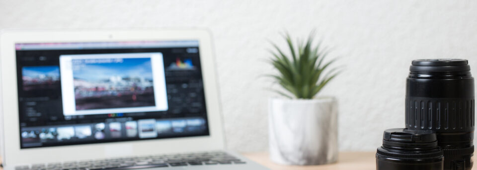 Professional photo editing software for Mac shown on laptop with camera lenses on desk