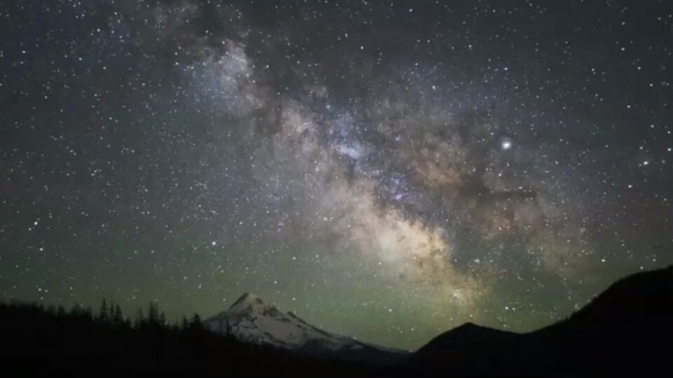 Milky Way galaxy arching over a mountain silhouette with pine trees edited in ON1 Photo RAW, demonstrating night sky landscape editing techniques including star enhancement, noise reduction, and contrast recovery